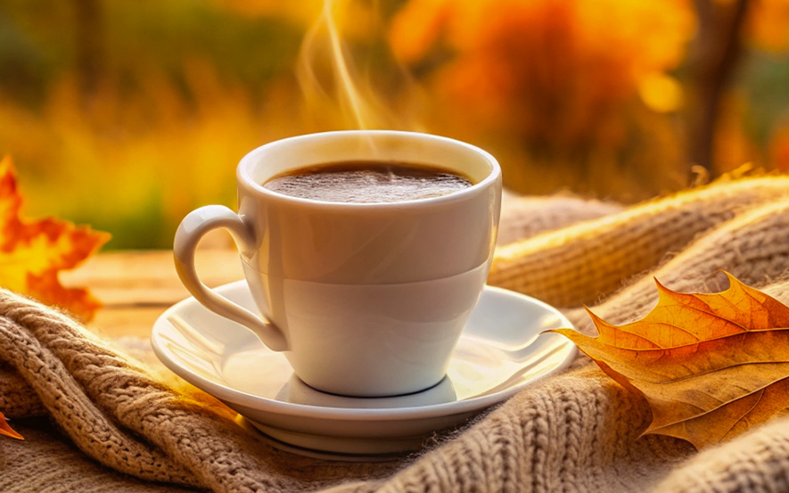Eine dampfende Tasse Kaffee auf einen Tisch mit braunen Blättern von Hof Schneider